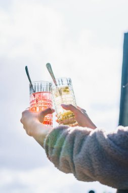 Üzerlerinde kokteyl ve kaşık dolu şeffaf bardaklar tutan bir çiftin dikey çekimi.