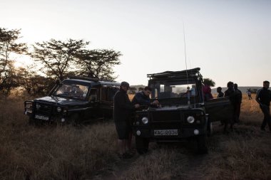 Kenya, Nairobi 'deki Masai Mara Ulusal Parkı' nda arabalarının yanında duran insanların yakın çekimi.