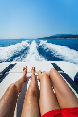 Mavi gökyüzünün altında denize bakan bir teknede dinlenen bir çift.