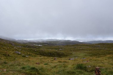 İskoçya 'da kasvetli bir gökyüzünün altındaki çimenli bir arazide bir kaya yığını.