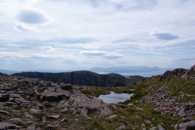 İskoçya 'da bulutlu bir günde, bir vadinin ortasında kayalarla çevrili güzel bir gölet..