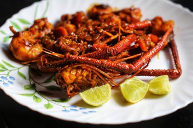 Siyah bir yüzeye izole edilmiş bir tabakta limonlu lezzetli bir ıstakoz körisinin yakın çekimi.