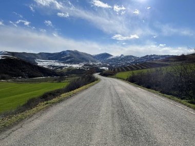 Uzaklarda dağ katmanları olan güzel arazi arazileri arasında boş bir yol.