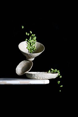 Soya fasulyesinin dikey görüntüsü siyah bir arka planda izole bir şekilde havada süzülüyor.