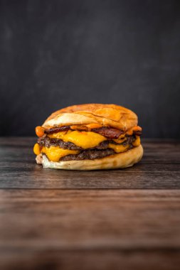 Tahta bir masada ezilmiş lezzetli bir hamburgerin dikey çekimi.