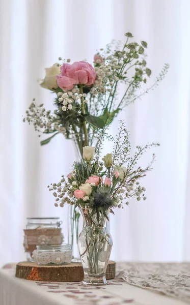白を基調としたテーブルの上に白とピンクのバラとガラスの花瓶の垂直ショットミニマリスティックな設定 — ストック写真