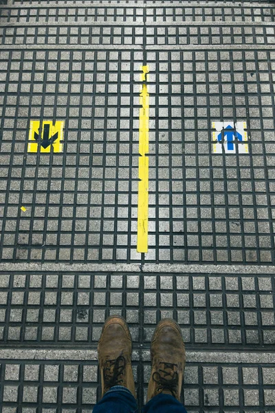 A vertical shot of man\'s feet on a pavement with small arrows