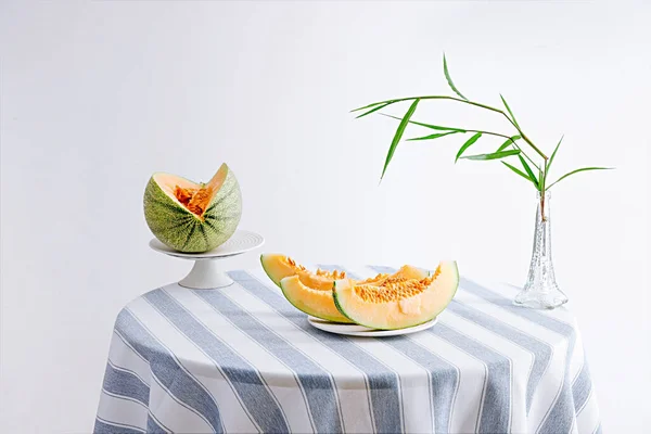 丸いテーブルの上の花瓶にメロンスライスと竹の葉の静物写真 — ストック写真