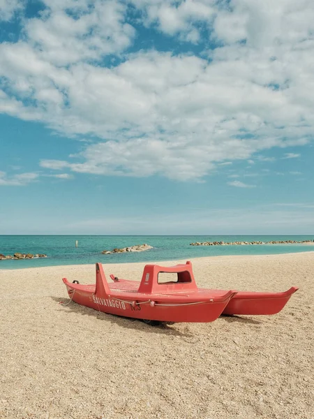 Pionowe Ujęcie Czerwonej Łodzi Ratowniczej Piaszczystej Plaży Pobliżu Wody Słonecznym — Zdjęcie stockowe