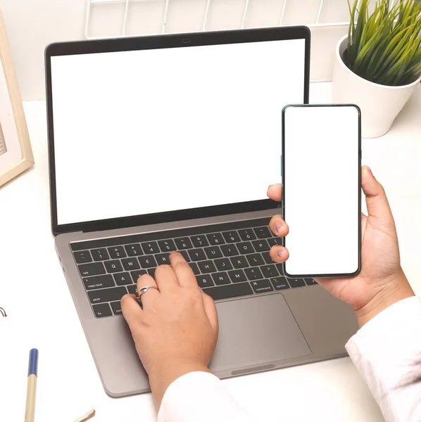 Ofiste boş ekranlı, dizüstü bilgisayar ve cep telefonu kullanan bir kadının yakın plan fotoğrafı.