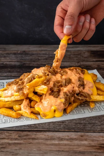 Closeup Shot Hand Picking Cheesy French Fries Wooden Table — Stock Photo, Image