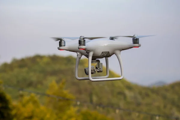 緑の山の背景に飛行中の無人機のクローズアップショット — ストック写真