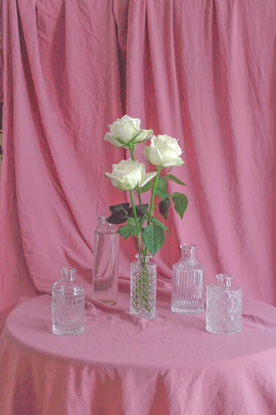 Vertical Shot White Roses Beautiful Glass Bottles Pink Fabric Surface — Stock Photo, Image