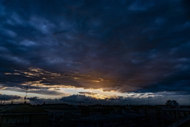 Gün batımında renkli gökyüzünde çarpıcı bir kara bulut manzarası.