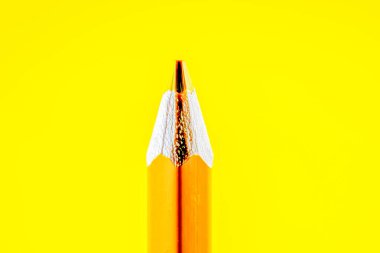 Sarı arka planda altın bir kalemin yakın çekimi.