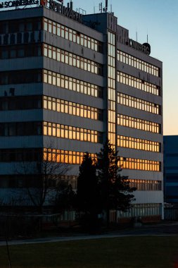 Yüzeyde gün batımının yansıması olan cam duvarlı bir binanın dikey görüntüsü.