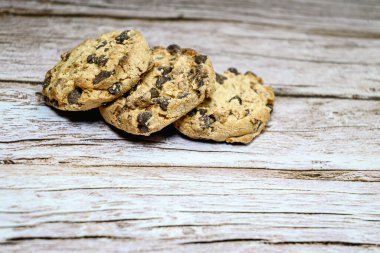 Köy ahşap bir masada izole edilmiş üç çikolatalı kurabiyenin yakın çekimi.