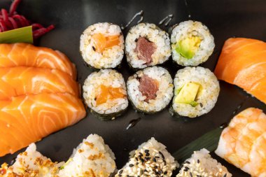 Beyaz arka planda siyah bir tabakta sushi 'nin üst görüntüsü