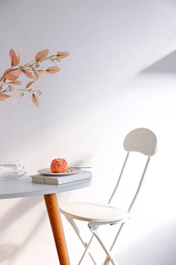 Bir kek parçasının dikey görüntüsü ve bir masanın üzerindeki çiçekler beyaz arka planda.