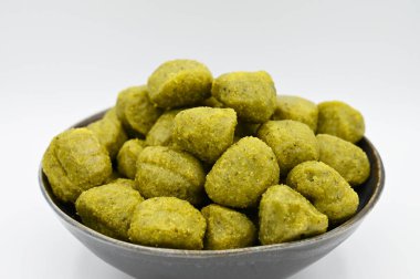 Beyaz bir yüzeyde izole edilmiş bir kasede pesto gnocchi 'nin yakın çekimi.