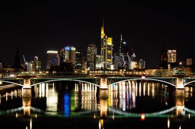 Ana nehir üzerinde bir köprü ve Frankfurt, Almanya 'da geceleri arka planda binalar.