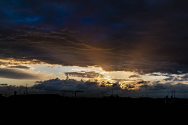 Gün batımında renkli gökyüzünde çarpıcı bir kara bulut manzarası.
