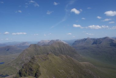 İskoç kırsalında parlak bulutlu bir gökyüzünün altında sarp yeşil tepelerin ve uçurumların güzel manzarası