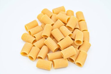 Beyaz arka planda beyaz bir kasede çiğ rigatoni makarnası.