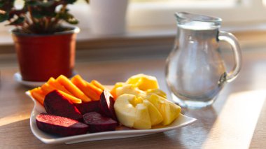 Bir tabak dolusu havuç, pancar, elma ve bir sürahi dolusu su.