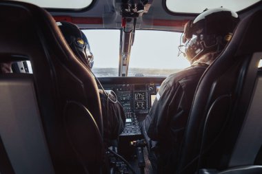 Pilot ve yardımcı pilot uçuş sırasında bir helikopter kokpitinde oturuyordu.