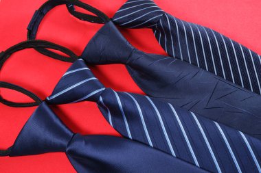 Kırmızı arka planda çeşitli desenlere sahip dört mavi kravat.