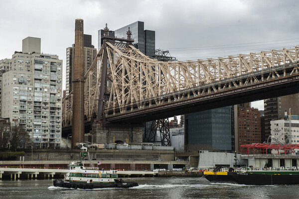 The Queensboro Bridge over the East River with ships on it on a gloomy day in New York City