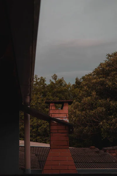 Bir Evin Çatısındaki Tuğla Bacanın Dikey Görüntüsü Ağaçlara Bulutlu Gökyüzüne — Stok fotoğraf