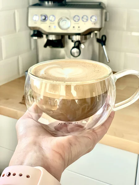 一杯卡布奇诺咖啡一种用老式咖啡机制作的拿着一杯卡布奇诺咖啡的人的垂直镜头 — 图库照片