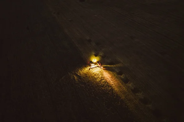 夜间在灯火通明的田里工作的收割机的空中无人驾驶镜头 — 图库照片