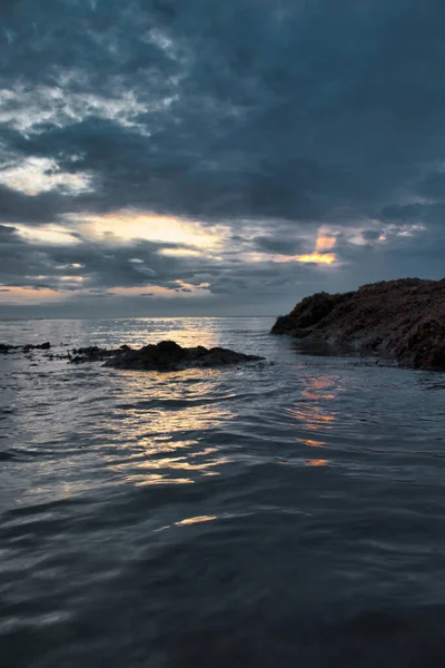 夕阳西下 在多云的天空下 岩石海岸的垂直拍 — 图库照片