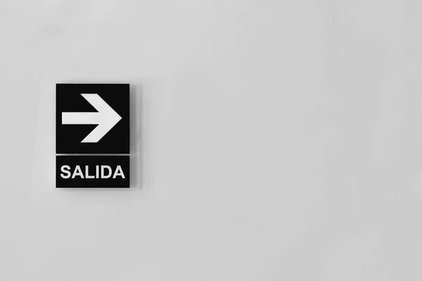 右矢印とスペイン語で出口 Salida のサインのグレースケールショット — ストック写真