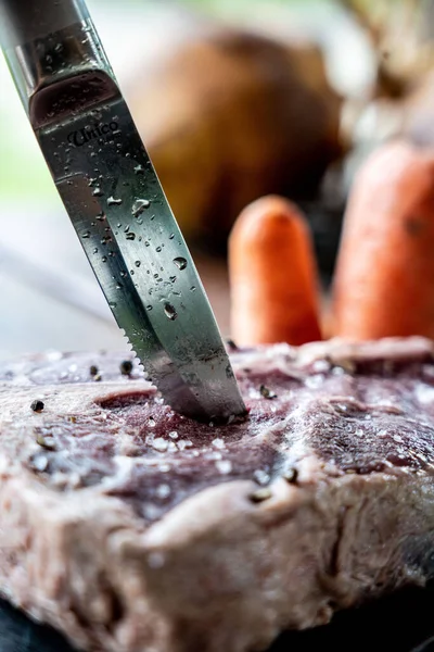 Çiğ Biftekteki Bıçağın Dikey Yakın Çekimi Tahta Bir Masanın Üzerindeki — Stok fotoğraf