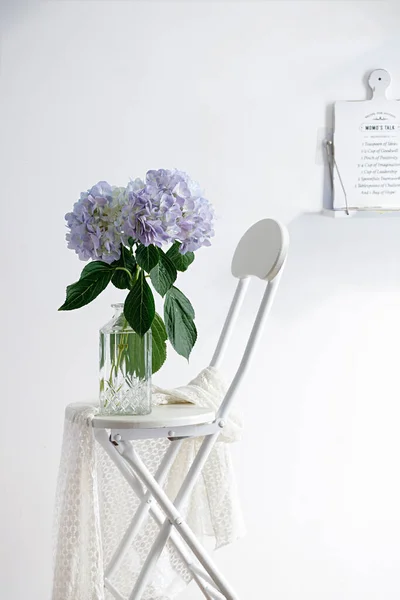 这个垂直画室拍摄的静物画 有一张白色的椅子和一个紫色花朵的花瓶 — 图库照片