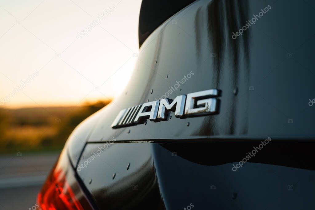 A closeup shot of a Mercedes Benz AMG Logo on a black car against a blurred background