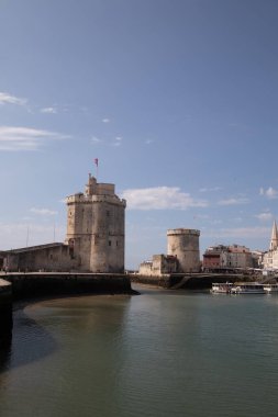 La Rochelle kulesinin mavi parlak gökyüzünün altında yüzen bir teknesi olan dikey görüntüsü.