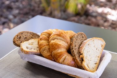 Ekmek parçaları ve kruvasan kumaş tabakta açılı bir çekim..