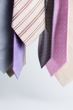 Gri arka planda asılı renkli erkek kravatlarının yakın çekimi