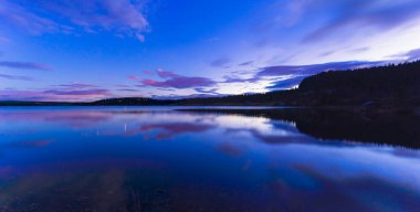 Güzel mavi bir gökyüzü ve ada durgun suya yansıyor.