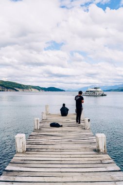 Erkeklerin iskelede ve geminin arka planda dikey görüntüsü.