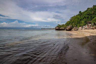 Deniz üzerindeki bulutlu gökyüzü Endonezya, Bali 'de bir sahilden rüzgarlı bir akşamda yakalandı.