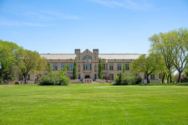 Bereketli yeşil tarlaları ve açık gökyüzünün altındaki ağaçları olan bir malikanenin manzarası.