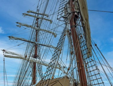 Mavi gökyüzü arka planında bir geminin kablo merdiveni olan eski bir yelkenli gemisinin direği.