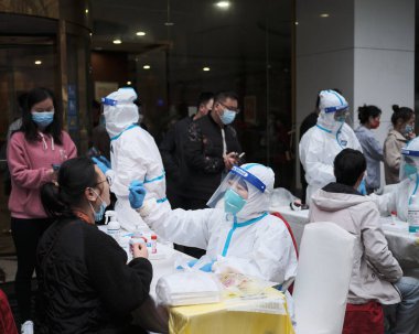 Bir Şangay şehri sağlık çalışanı, sakinlerin covid testine yardım ediyor.
