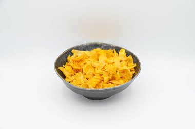 Beyaz bir yüzeyde izole edilmiş bir kasede gevrek mısır gevreğinin yakın çekimi.